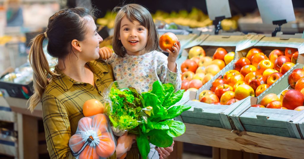 Niña aprendiendo nombres de frutas en inglés con su madre